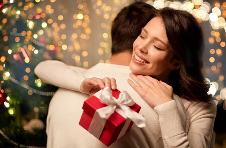 happy couple with christmas gift hugging at home