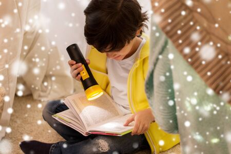 happy boy reading book in kids tent at homeの写真素材