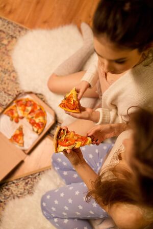 happy female friends eating pizza at homeの写真素材