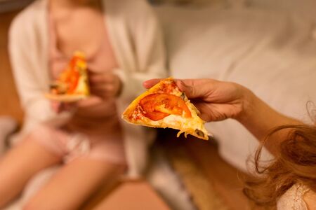 happy female friends eating pizza at homeの写真素材