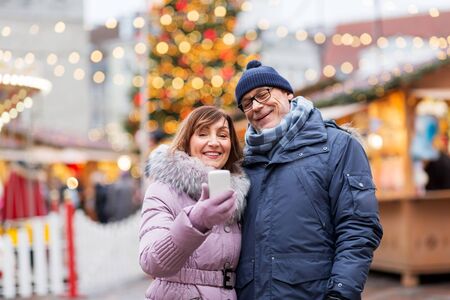 senior couple taking selfie at christmas marketの写真素材