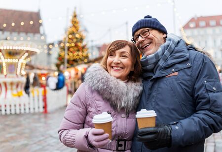 senior couple with coffee at christmas marketの写真素材