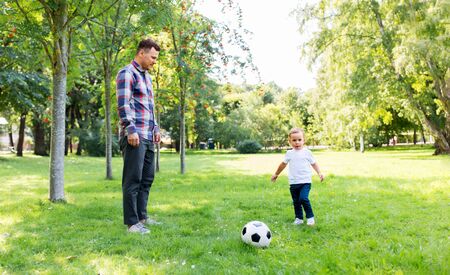 father with little son playing soccer at parkの写真素材