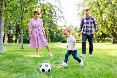 happy family playing soccer at summer parkの写真素材