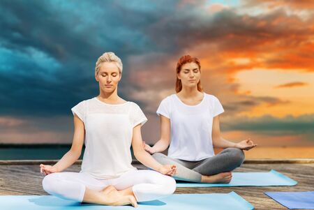 women meditating in yoga lotus pose outdoorsの写真素材
