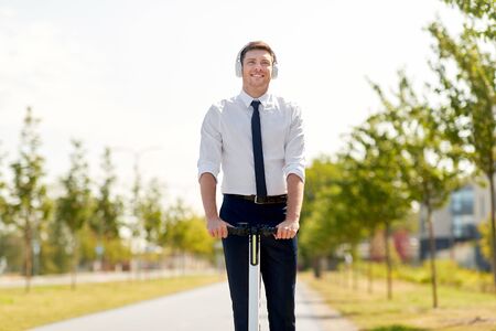 businessman with headphones riding scooter in cityの写真素材