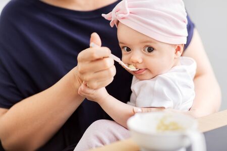 middle-aged mother feeding baby daughter at homeの写真素材