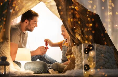 family playing tea party in kids tent at homeの写真素材