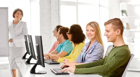 A group of happy international high school students or classmates in computer class