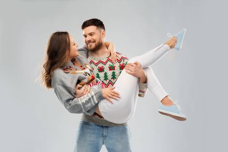 christmas, people and holidays concept - happy couple at ugly sweater partyの写真素材