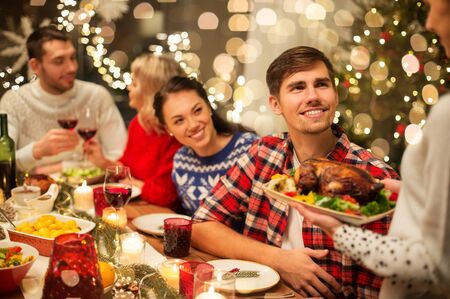 holidays and celebration concept - happy friends having christmas dinner at homeの写真素材