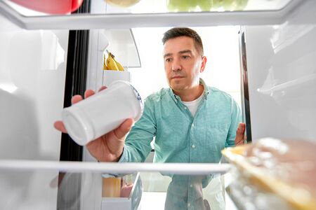 man taking food from fridge at kitchenの写真素材