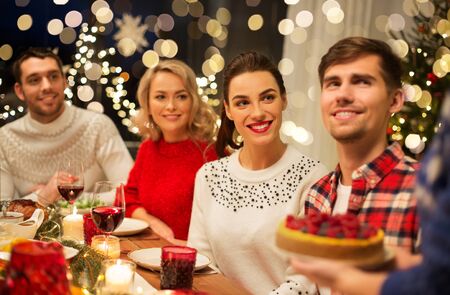 holidays and celebration concept - happy friends having christmas dinner at homeの写真素材