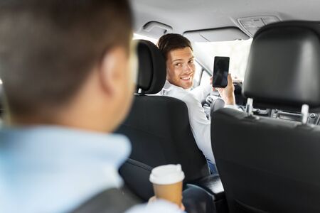 transportation, vehicle and technology concept - smiling car driver showing smartphone to male...
