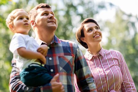 family, leisure and people concept - happy mother, father and little son at summer parkの写真素材
