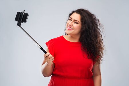 woman taking picture by smartphone on selfie stickの写真素材