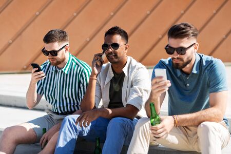 men with smartphones drinking beer on street