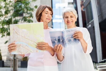 senior women with city guide and map on streetの写真素材