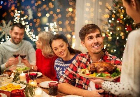 happy friends having christmas dinner at homeの写真素材