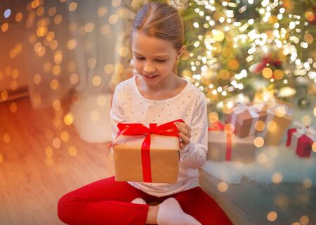 smiling girl with christmas gift at homeの写真素材