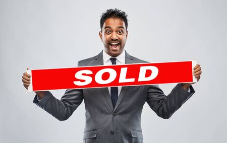 happy indian male realtor with red sold bannerの写真素材