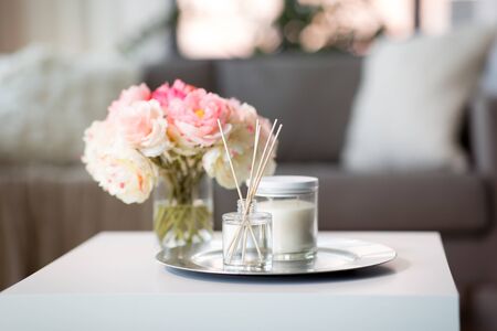 aroma reed diffuser, candle and flowers on table
