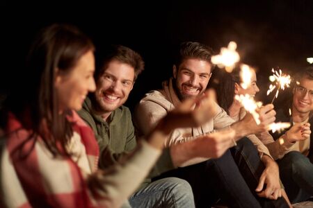 celebration, holidays and people concept - happy friends with sparklers at night outdoors