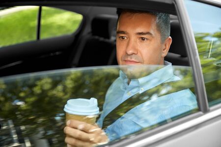 man drinking takeaway coffee on car back seat
