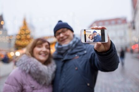 senior couple taking selfie at christmas marketの写真素材