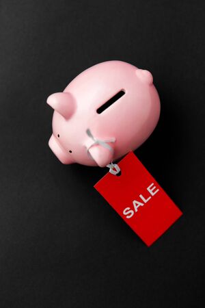 shopping, marketing and saving concept - piggy bank with red sale tag on black backgroundの写真素材