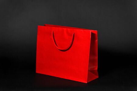 sale, consumerism and outlet concept - red shopping bag on black backgroundの写真素材