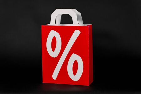 sale, consumerism and outlet concept - red shopping bag with percentage sign on black backgroundの写真素材
