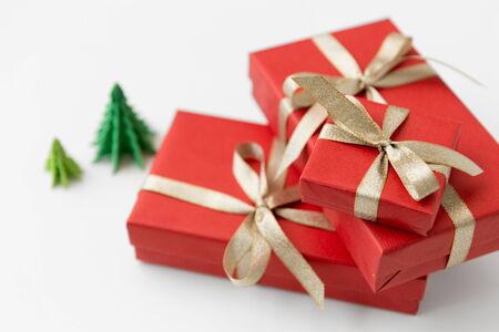 winter holidays, new year and celebration concept - red gift boxes and origami christmas trees on white backgroundの写真素材