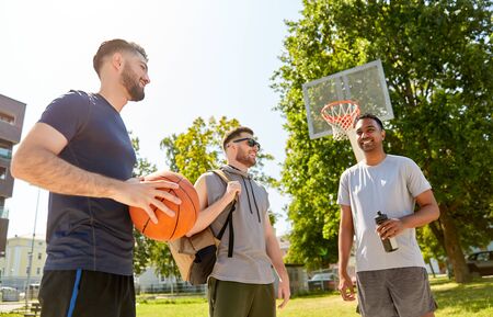 sport, leisure games and male friendship concept - group of men or friends going to play basketball outdoorsの写真素材