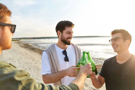 young men toasting non alcoholic beer on beach