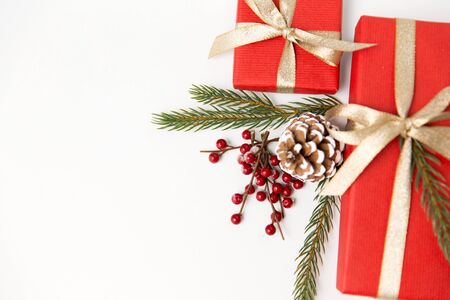 winter holidays, christmas and celebration concept - red gift boxes and fir tree branches with pine...