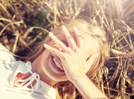 happy young woman lying on cereal fieldの写真素材