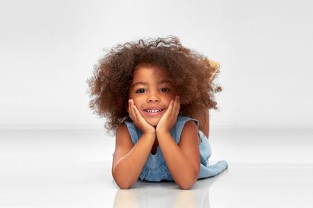 happy little african american girl lying on floorの写真素材