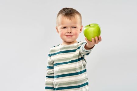 portrait of smiling boy holding green appleの写真素材