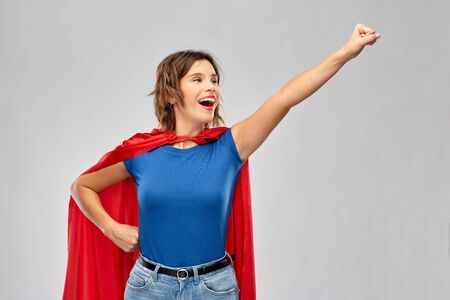 happy woman in red superhero capeの写真素材