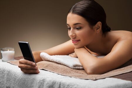 woman with smartphone at spa or massage parlorの写真素材