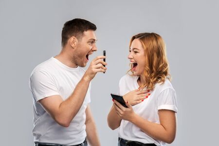 Happy couple in white t-shirts with smartphones