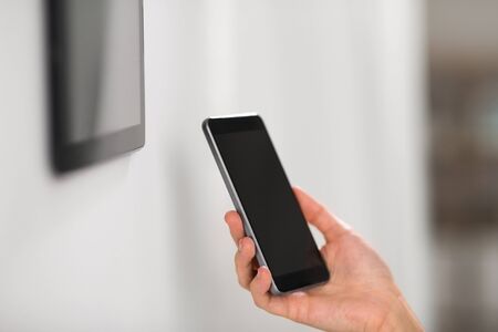 automation, internet of things and technology concept - hand with smartphone at smart homeの写真素材