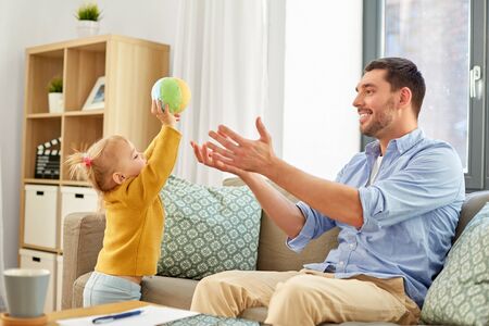 father and baby daughter playing with ball at home