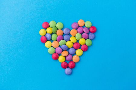 candy drops in shape of heart on blue backgroundの写真素材