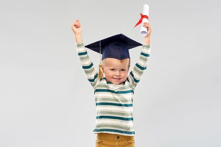 smiling little boy in mortar board with diplomaの写真素材