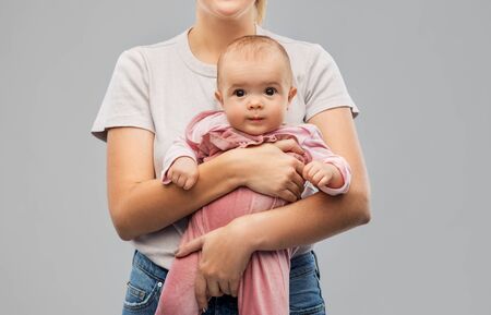 family, child and parenthood concept - happy smiling young mother holding little baby daughter over...