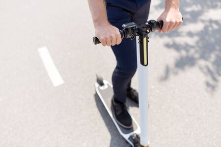 business and people and concept - close up of young businessman riding electric scooter outdoors