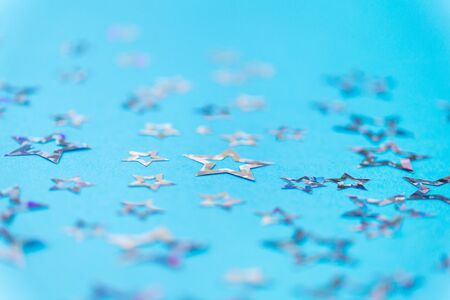 party, celebration and decoration concept - holographic star shaped confetti on blue background