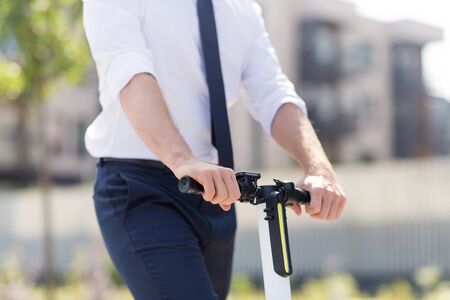 Young businessman riding electric scooter outdoorsの写真素材